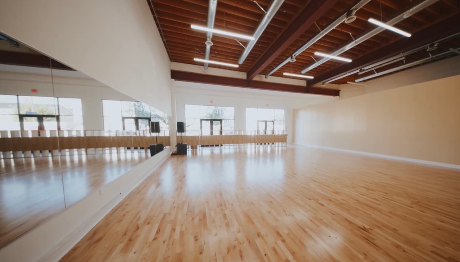 The Dream Big Dance studio floor with a wall of mirrors and exposed wood ceiling